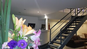 A modern interior with a staircase, a reception desk, and a plant with flowers. - Hotel Avenida (Buenos Aires)