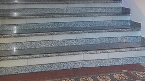 A staircase with granite steps leading to a landing with a white reception desk. - Hotel Avenida (Buenos Aires)