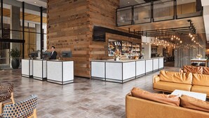 A spacious lobby with a reception desk, seating area, and a bar. - Rydges Fortitude Valley (Bowen Hills)