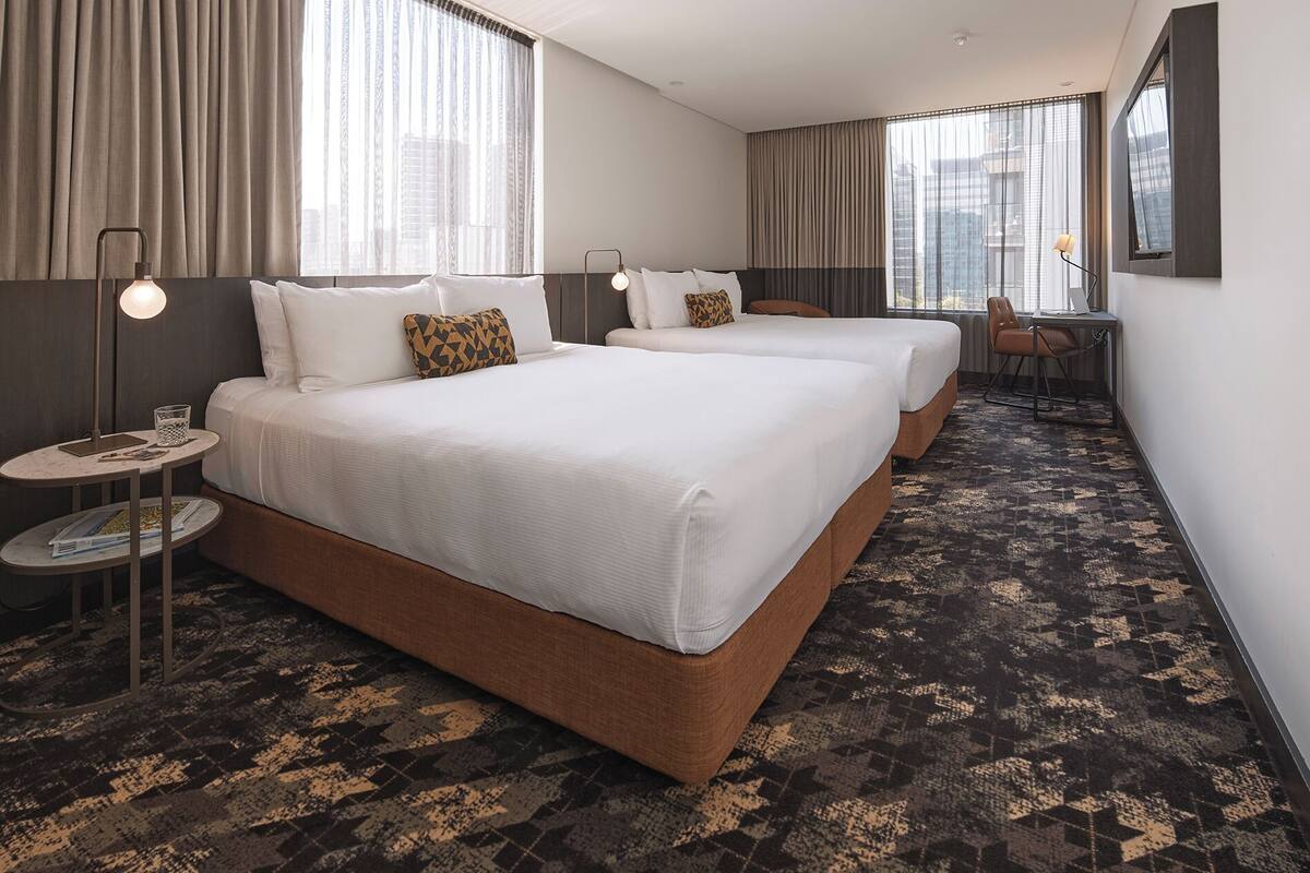 A hotel room with two beds, a desk, and a chair.