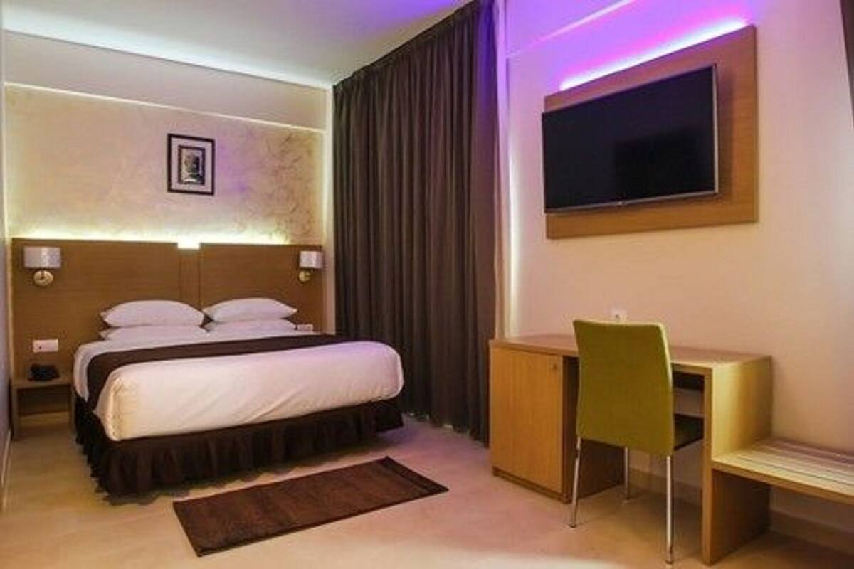Una habitación de hotel con una cama, un escritorio, una silla y un televisor.