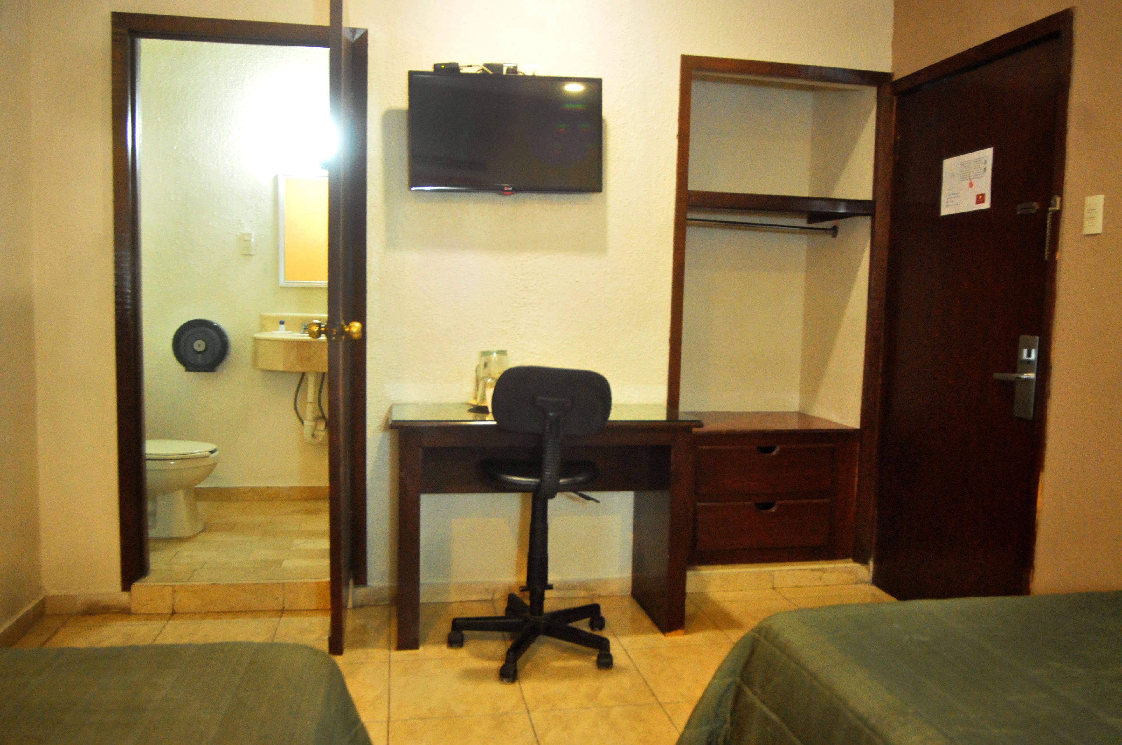 A room with a bed, a desk with a chair, a television, and a wardrobe.