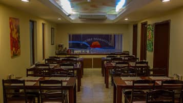 A conference room with tables and chairs, a large window with a view, and a ceiling with a light fixture.