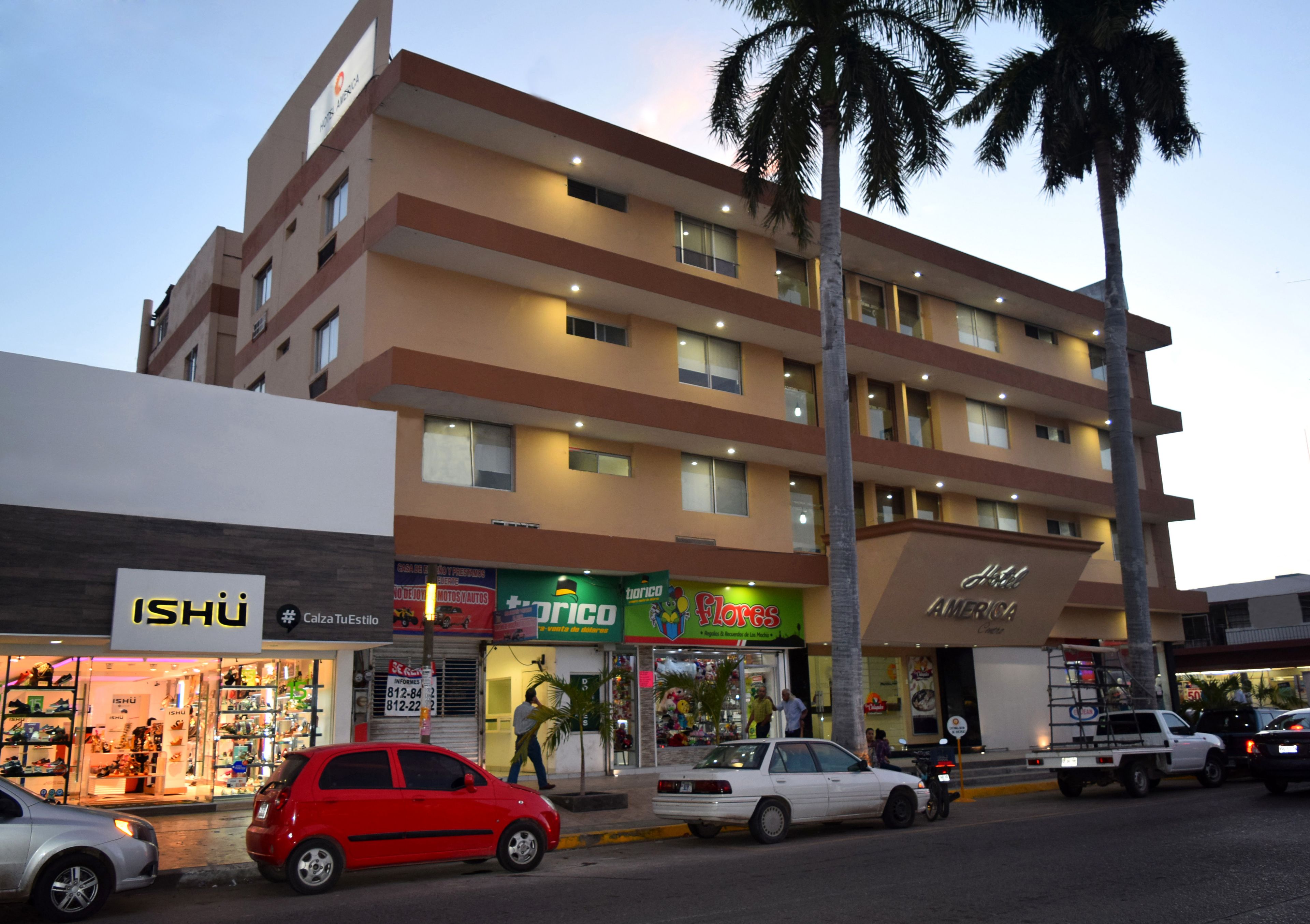 Un hotel de varios pisos con varias tiendas en la planta baja, incluyendo una zapatería y una juguetería.