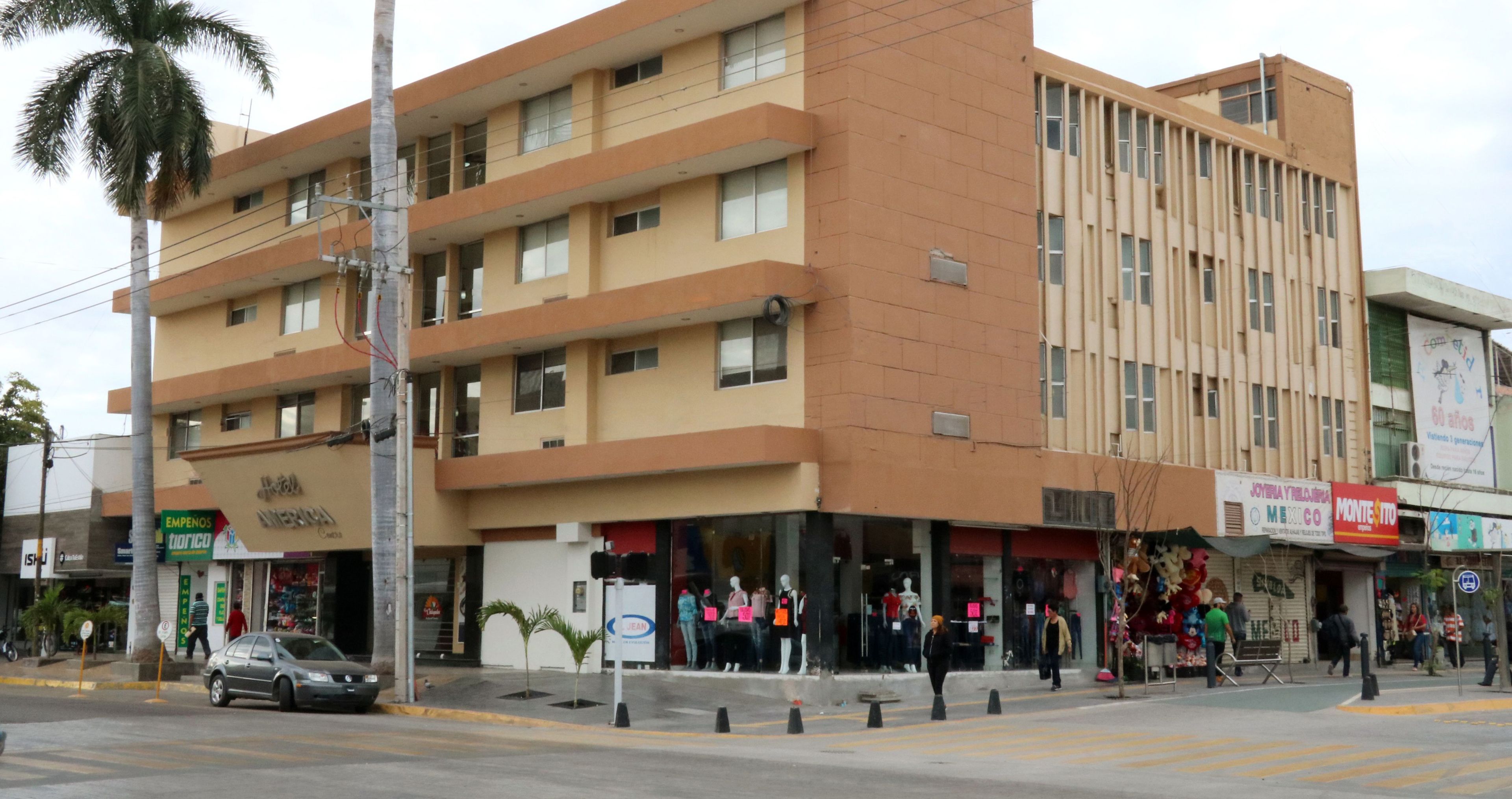 A multi-story building with a ground floor featuring various shops and a visible entrance.