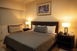 A hotel room with a large bed, two bedside tables with lamps, a wall-mounted air conditioner, and a framed abstract painting. - Hotel America Centro (Los Mochis)