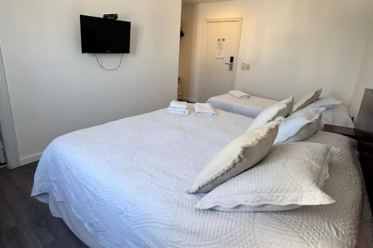 A hotel room with a large bed, a flat-screen TV mounted on the wall, and a door leading to a bathroom.