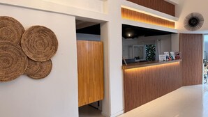 A reception area with a wooden reception desk, a wall-mounted clock, and a circular woven wall decoration. - Hotel Azul Puerto Punta del Este (Punta del Este)
