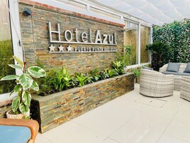 A hotel entrance with a stone facade, a sign reading "Hotel Azul Puerto Punta del Este," and outdoor wicker furniture.