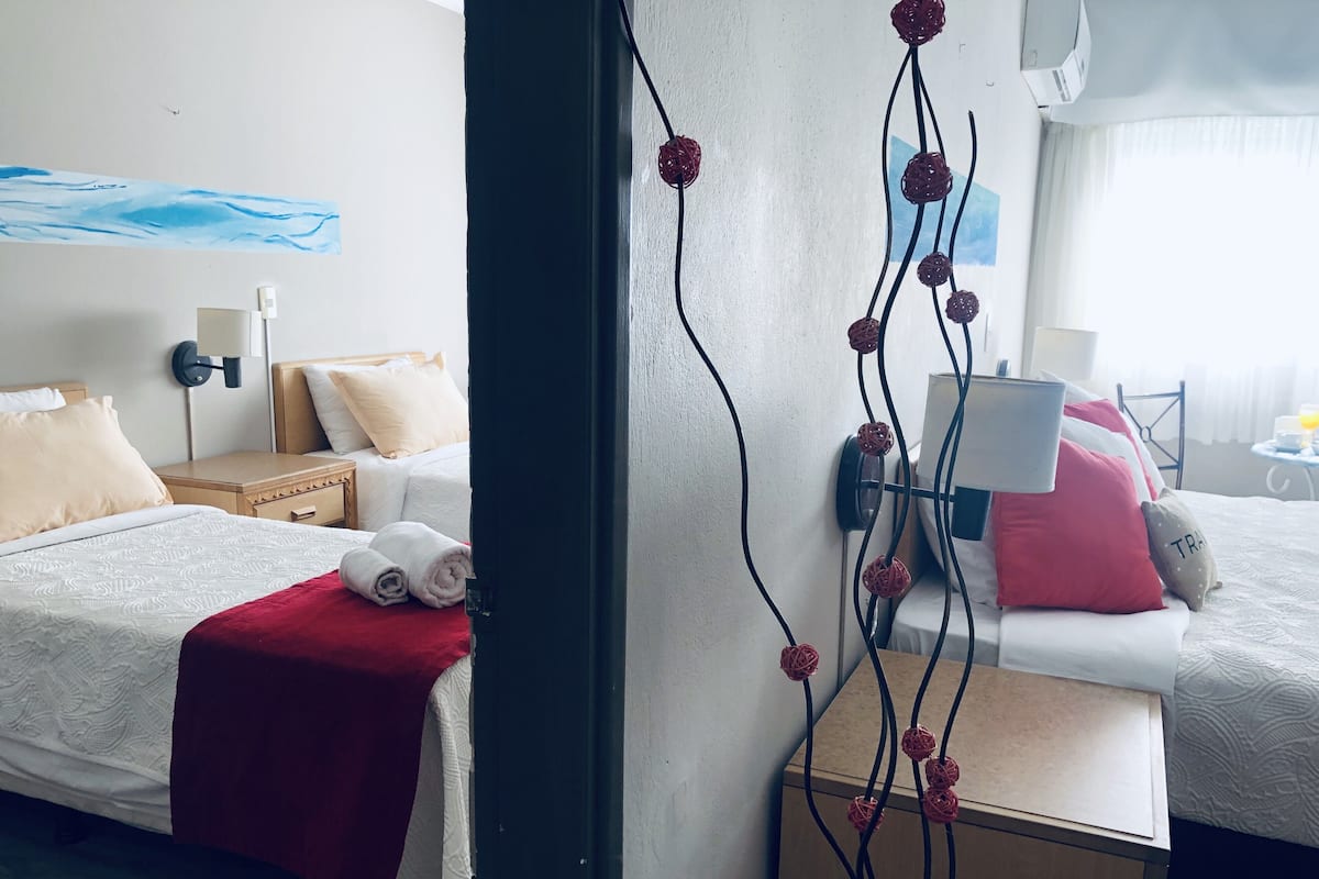 A hotel room with a bed, bedside table, lamp, and a wall with a painting.