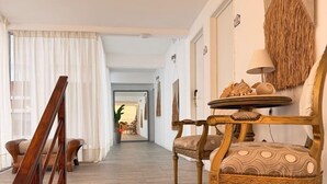 A spacious hallway with a wooden staircase, a dining area with a table and chairs, and a view into another room. - Hotel Azul Puerto Punta del Este (Punta del Este)