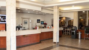 A hotel lobby with a reception desk, seating area, and a trash bin. - Continental Inn & Suites (Edmonton)