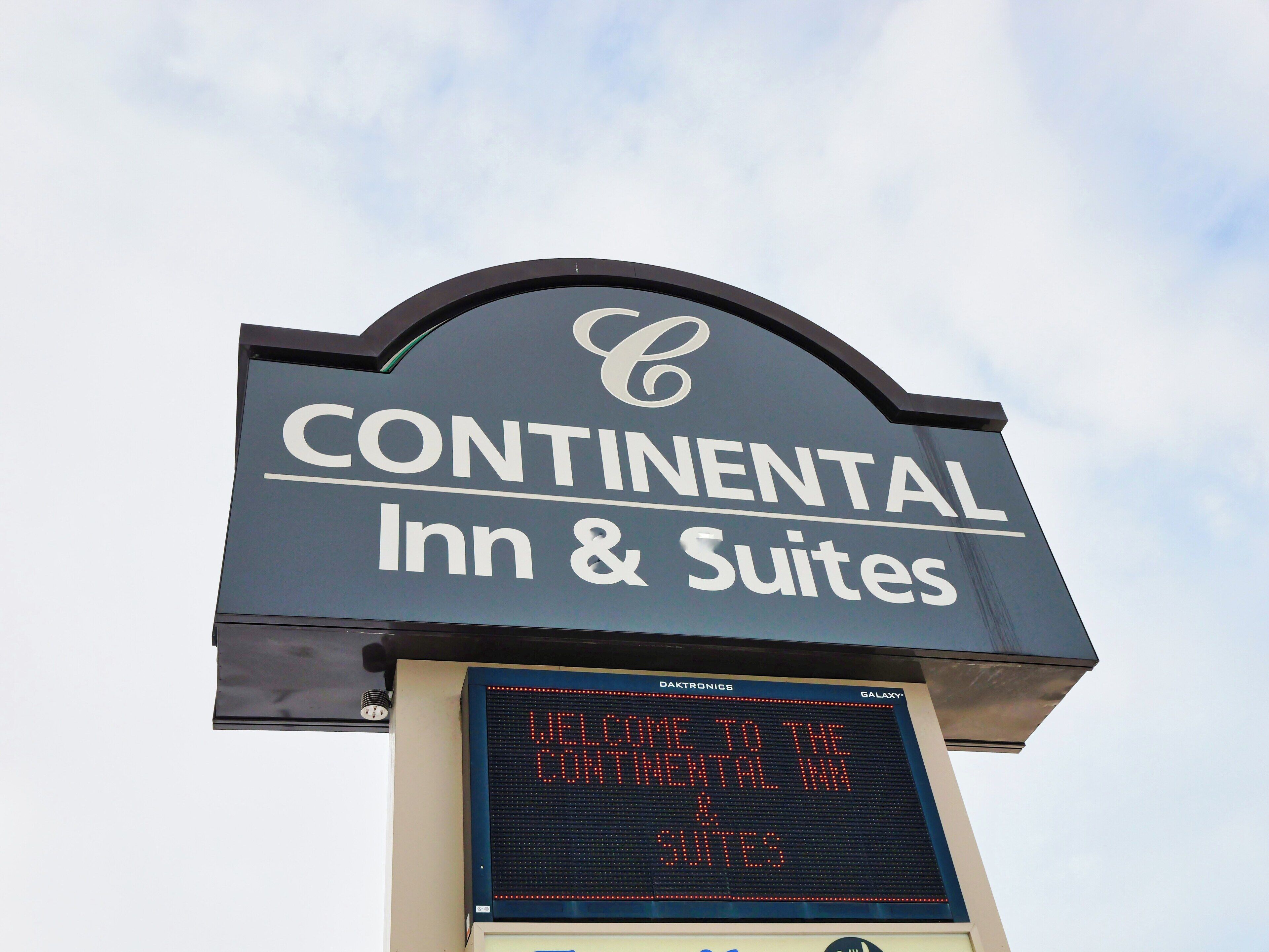 Señal de Continental Inn & Suites con un mensaje de bienvenida digital.