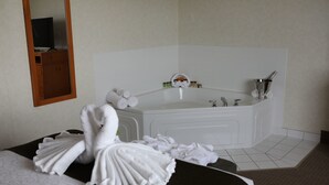 A hotel room with a bed, a large bathtub, and a mirror. - Continental Inn & Suites (Edmonton)