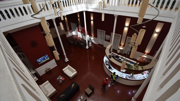Een ruime lobby met een centraal zitgedeelte, een receptiebalie en een hoge plafond met decoratieve verlichting.