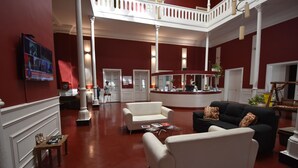 Een ruime lobby met rode muren, witte meubels en een centraal gelegen receptiebalie.