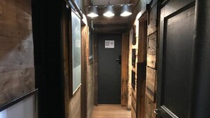 A narrow hallway with wooden walls and doors, a wooden floor, and overhead lighting. - Tremo Hotel Boutique Bellas Artes (Santiago)