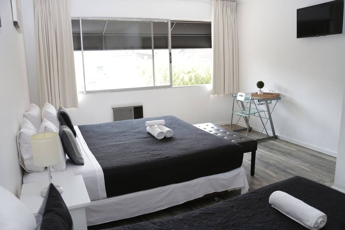 Una habitación de hotel moderna con una cama grande, un escritorio pequeño y un televisor montado en la pared.