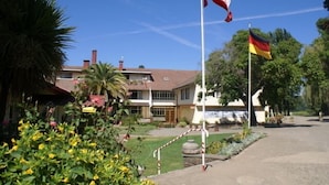Un edificio con asta de bandera y una bandera, incluyendo la bandera alemana.