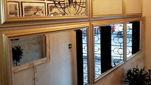 Een meerlaags interieur met een kroonluchter, ingelijste foto’s en een rode bank.