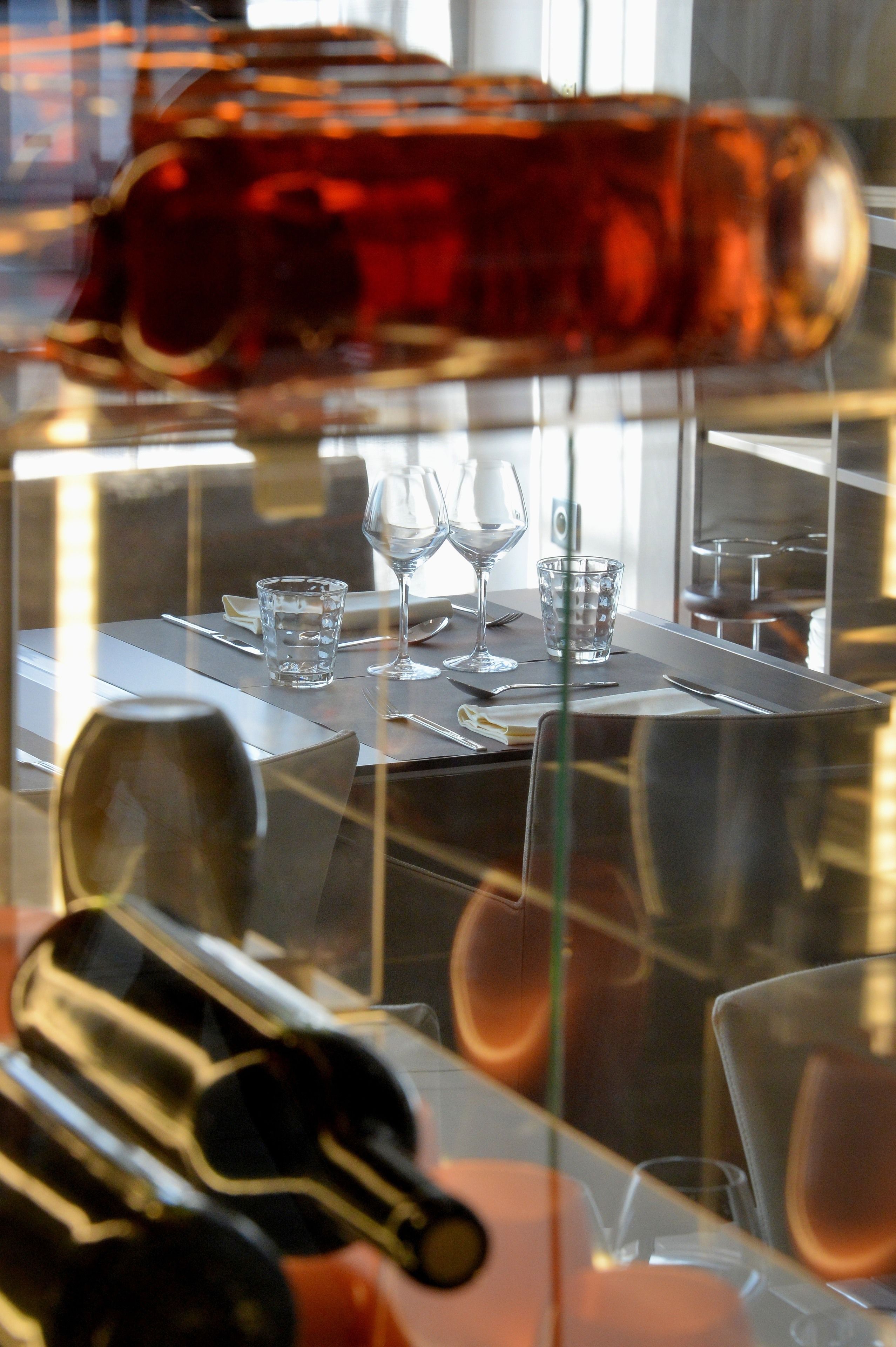 A dining table with a wine bottle, glasses, and cutlery.