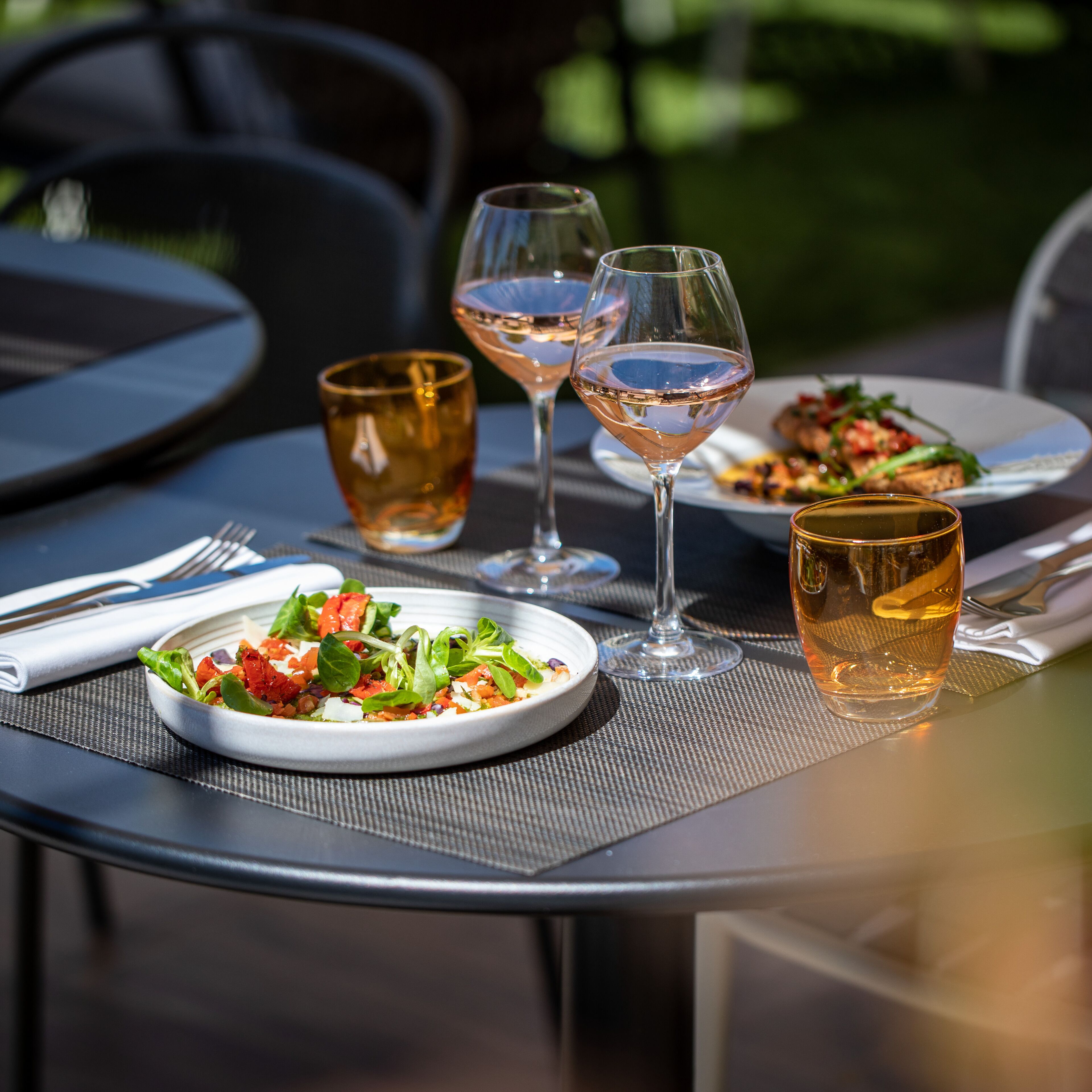 Une table à manger avec des assiettes remplies de nourriture, des verres de vin et un verre de bière.