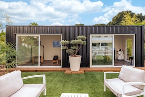 A modern container home with sliding glass doors, a small patio with white furniture, and a large potted tree. - AC Hotel by Marriott Marseille Prado Velodrome (Marseille)