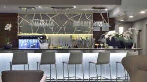 A modern bar area with a bar counter, seating, and a decorative light fixture. - AC Hotel by Marriott Marseille Prado Velodrome (Marseille)