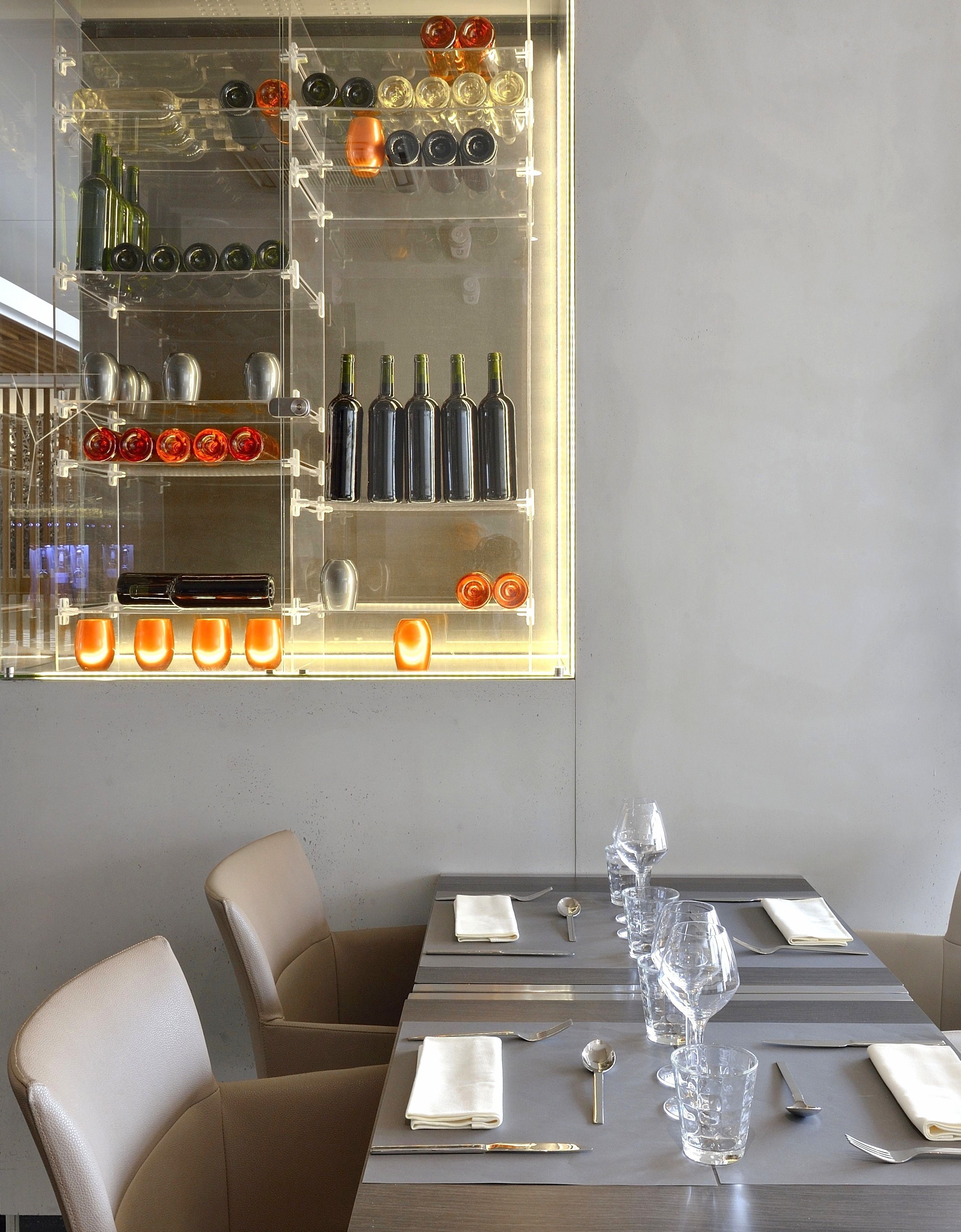 Comedor con una mesa dispuesta para dos personas, una vinoteca arriba y vistas de la ciudad.