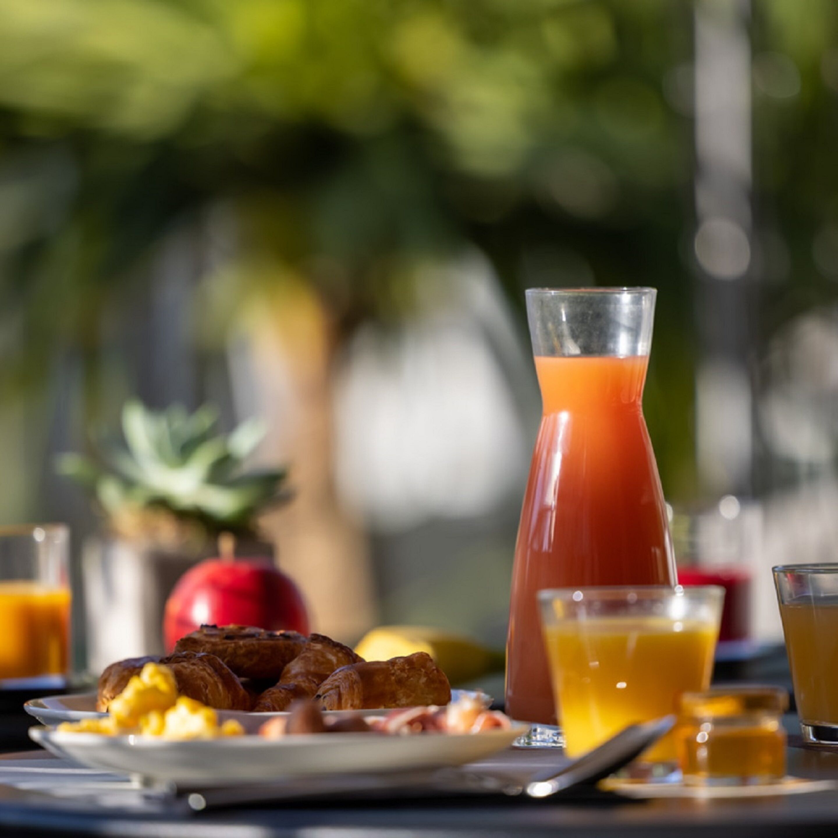 A breakfast table with croissants, a glass of orange juice, and a glass of tomato juice.