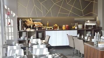 Un restaurante moderno con una barra central, sillas blancas y un diseño geométrico en el techo.