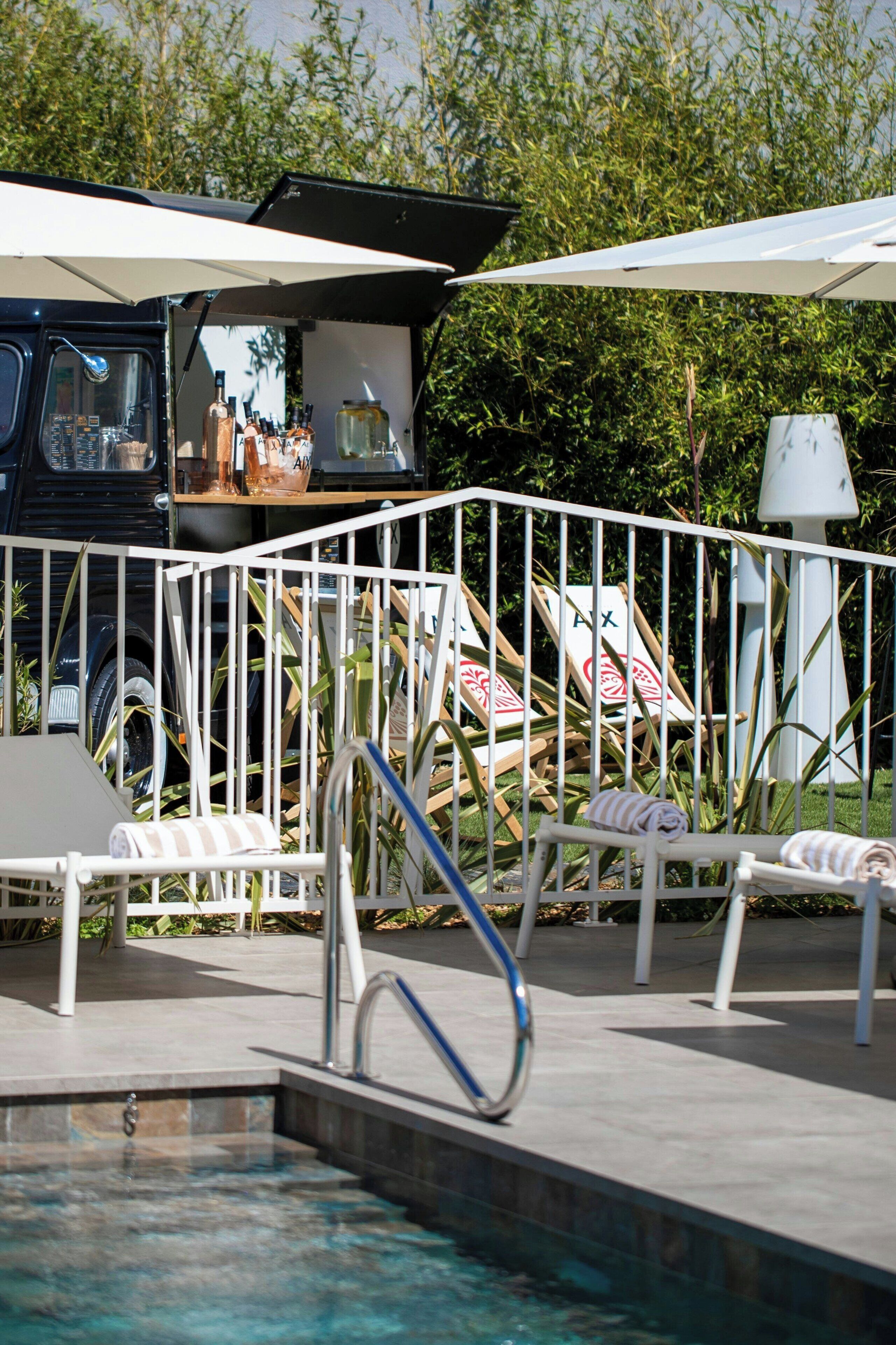 Un espace piscine avec des chaises longues et un petit coin bar agrémenté de parasols.
