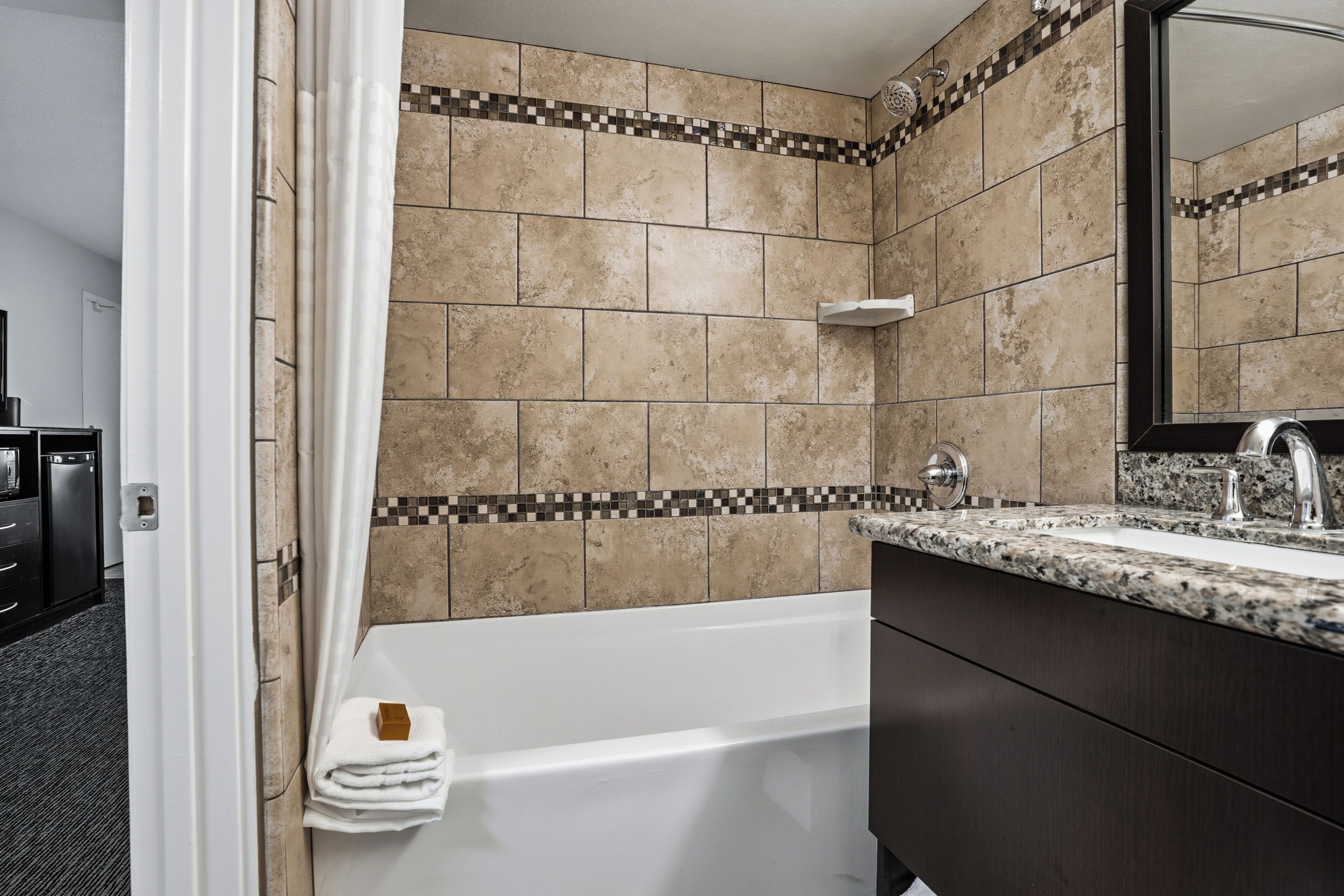 A bathroom with a bathtub, a sink with a mirror, and a towel rack.