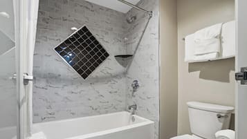 A bathroom with a white bathtub, a toilet, and a shower with a black and white patterned tile wall.