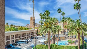 A hotel with a pool, palm trees, and a parking lot.