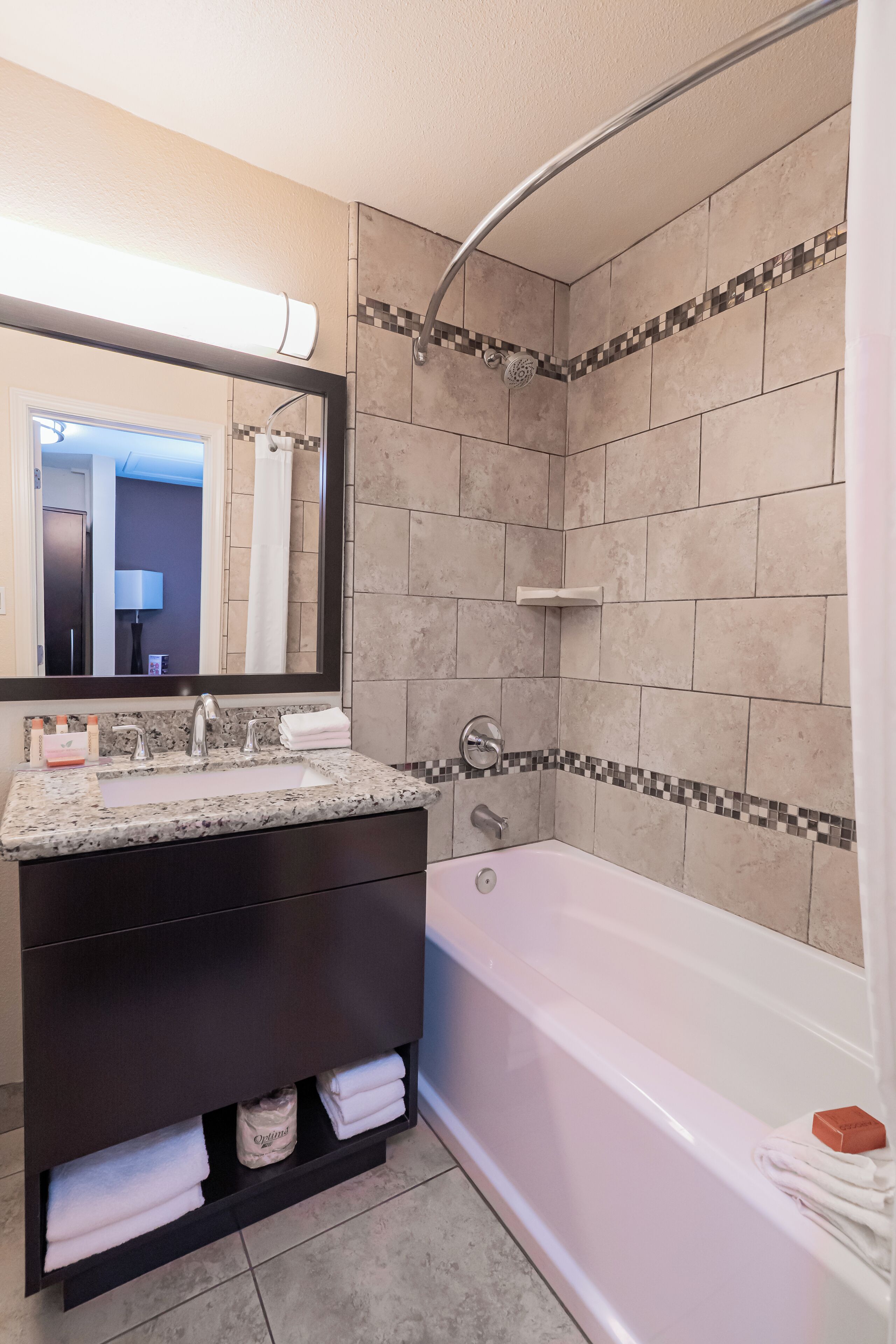 A modern bathroom with a freestanding bathtub, a vanity with a mirror, and a tiled shower area.