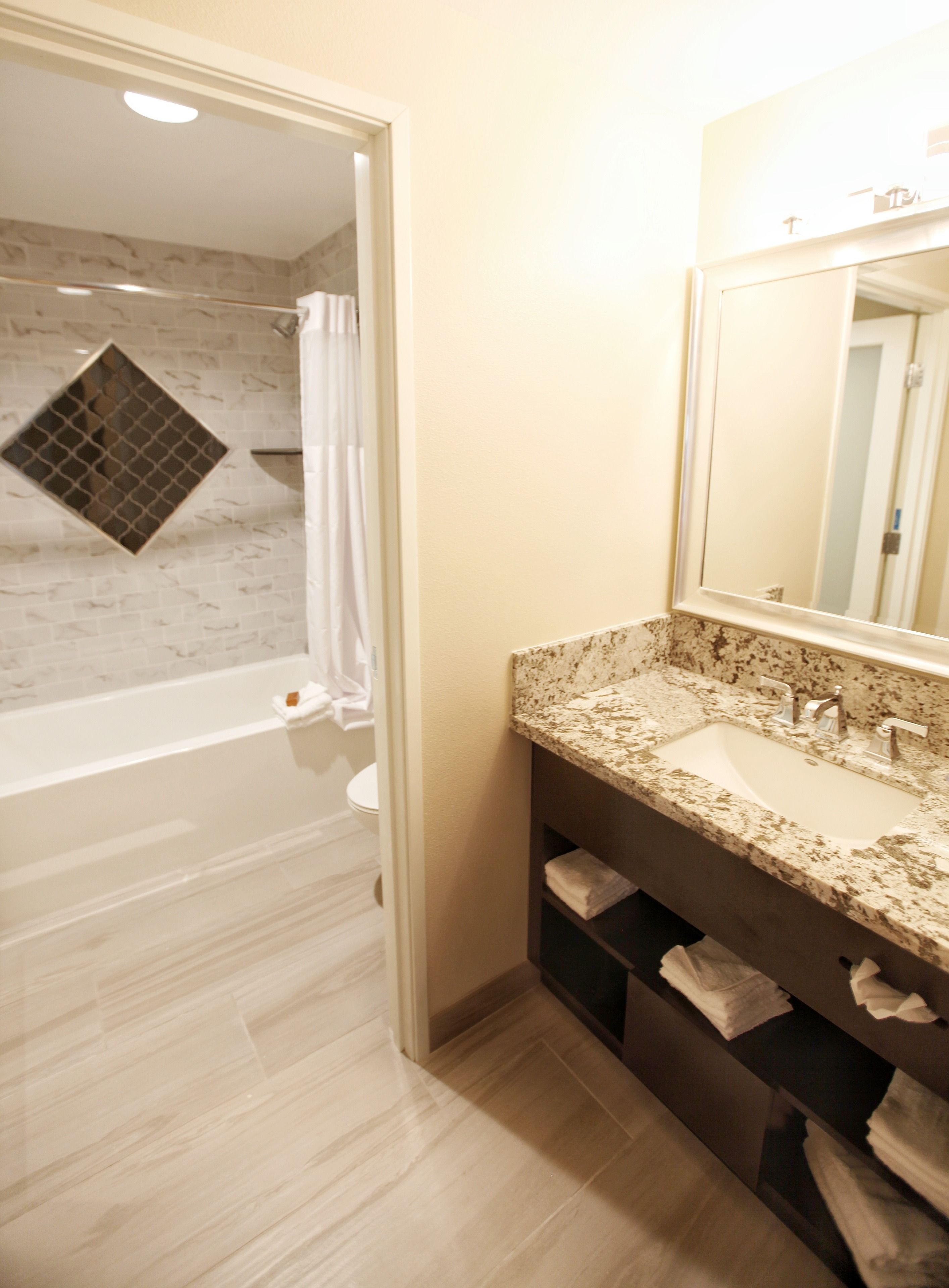 A bathroom with a bathtub, a sink, a mirror, and a shower curtain.