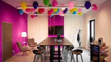 Un salón de conferencias con una larga mesa, varias sillas y globos de colores.