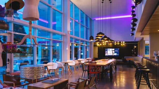 Een modern restaurant met grote ramen, een bar en een zithoek.
