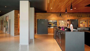 Een moderne bar met een houten plafond, een toog en een barman.