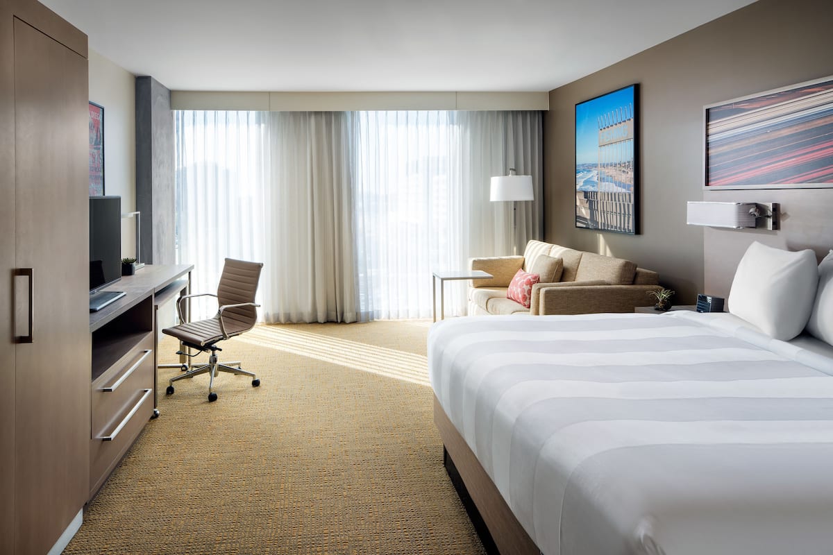 Una habitación de hotel con una cama grande, un escritorio con una silla, un sofá y un televisor.