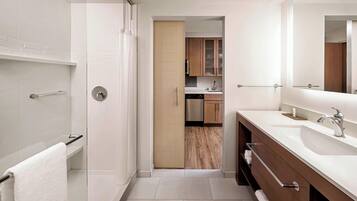 A modern bathroom with a walk-in shower, a double sink vanity, and a large mirror.