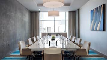 Uma sala de conferência com uma mesa comprida, cadeiras, uma planta e uma placa com a inscrição 'Residence Inn'.