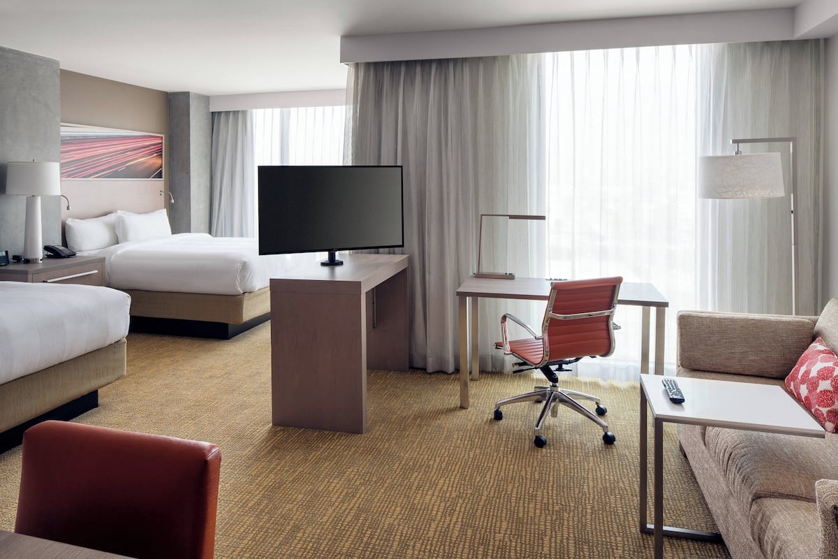 Una habitación de hotel con cama, escritorio, silla, televisor y sofá.