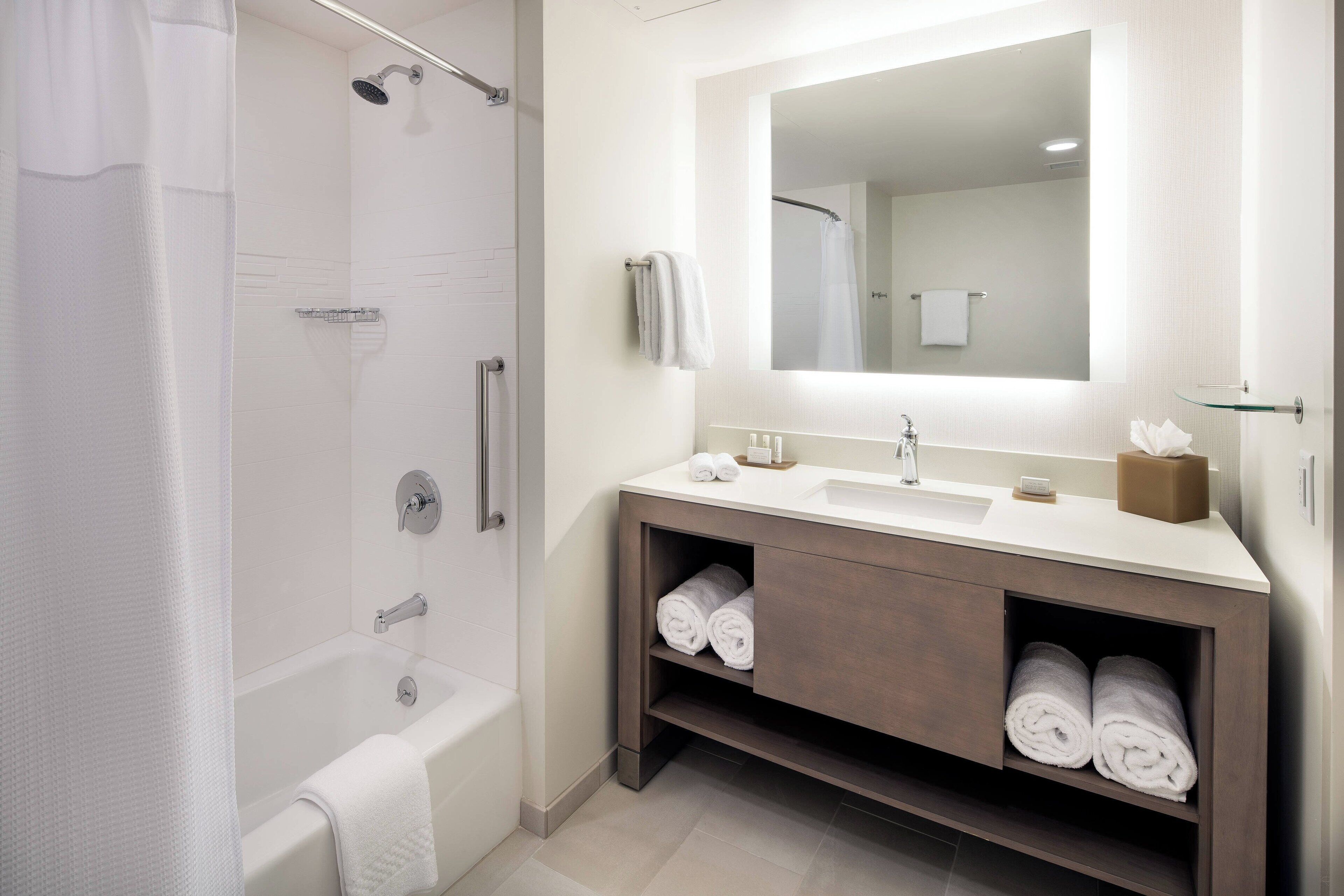 A modern bathroom with a bathtub, shower, and vanity with a mirror.