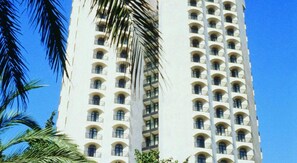 A tall white building with multiple balconies and arched windows.