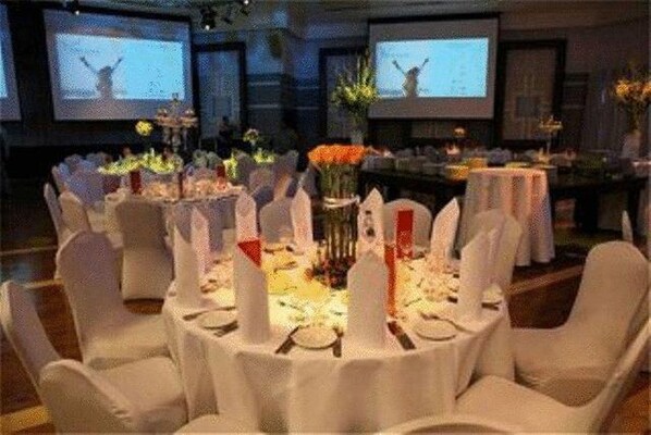 A banquet hall with round tables set for a formal event, equipped with screens displaying content. - Vert Jerusalem (Jerusalem)