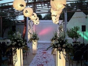 Une allée pour une cérémonie de mariage en plein air, agrémentée de compositions florales et d’un fond blanc.