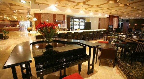 A hotel lobby with a piano, a bar area, and seating arrangements. - Vert Jerusalem (Jerusalem)