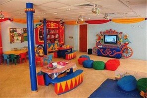 A children's play area with colorful furniture, a large blue pillar, and a television screen. - Vert Jerusalem (Jerusalem)